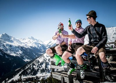 Drei Skifahrer in Lederhosen vor der Skihütte