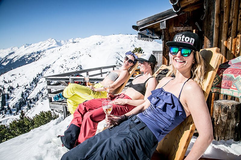 Skifahrerinnen sonnen sich vor der Skihütte