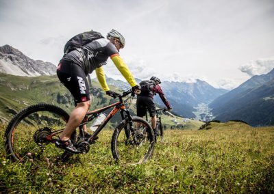 Zwei Mountainbiker auf einer Alm-Wiese